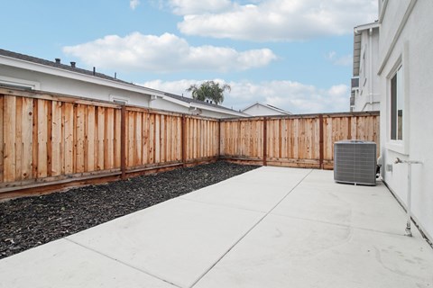 A backyard with a wooden fence and a white wall.
