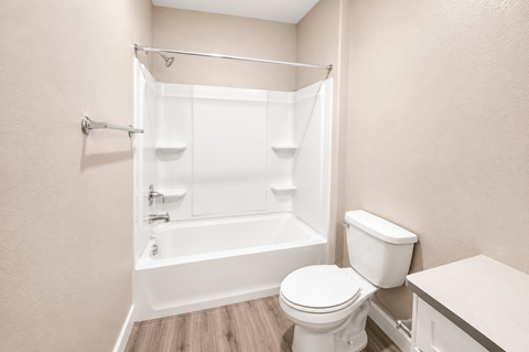 A white toilet sits next to a bathtub in a bathroom.