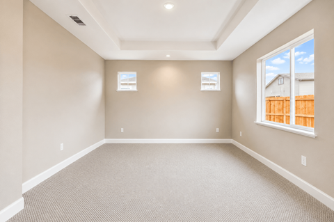 A large empty room with carpeted floor and two windows.