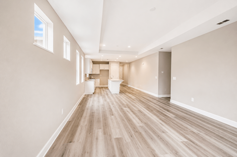 A long, empty room with wooden floors and white walls.
