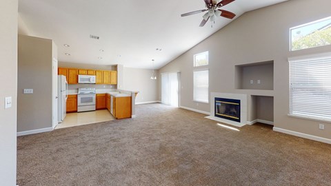 A spacious living room with a fireplace and a ceiling fan.