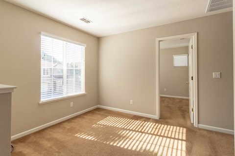 A room with a carpeted floor and a door leading to another room.