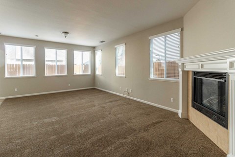 A living room with a fireplace and carpeted floor.
