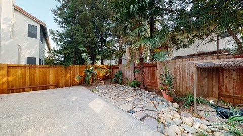 A backyard with a stone pathway and a wooden fence.