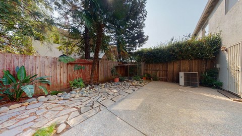 A backyard with a stone pathway and a fence.