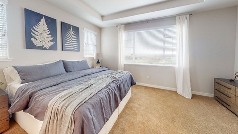 A bedroom with a bed, two wall art pieces, a nightstand, and a window with curtains.