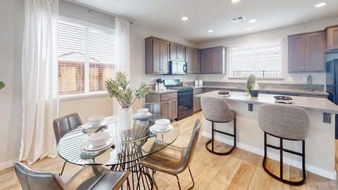 A modern kitchen with a dining table set for two.