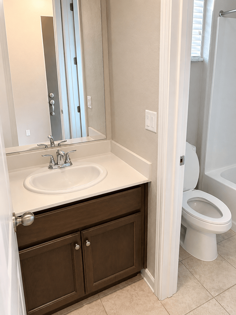 A white sink with a silver faucet and a white toilet in a bathroom.