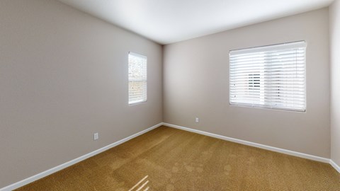 A room with a window and a carpeted floor.