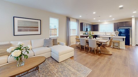 A modern living room with a white sofa, a coffee table, and a dining table set up.