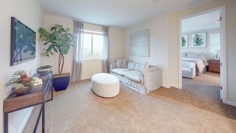 A living room with a white couch and a round ottoman.