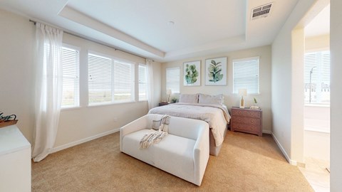 A bedroom with a large bed and a window with curtains.