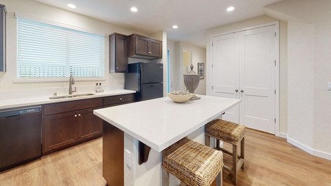A kitchen with a white table and brown chairs.