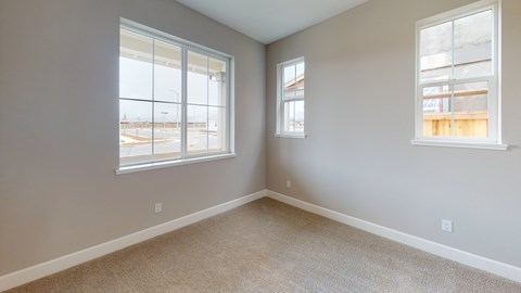 A room with two windows and carpeted floor.