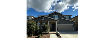 A grey house with a brown front yard.