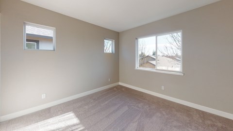 A room with two windows and carpeted flooring.