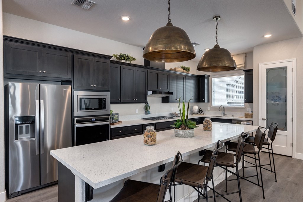 a kitchen with stainless steel appliances and a large island with chairs at Heritage Landing Apartments, California, 95973
