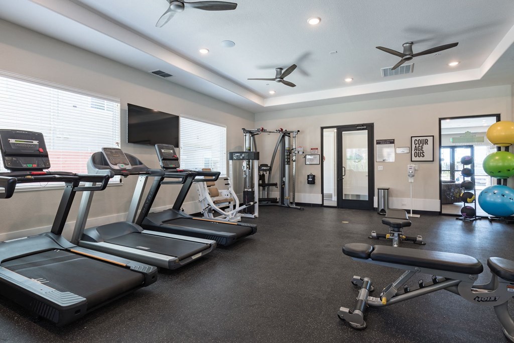 an exercise room with treadmills and weights and a tv at Heritage Landing Apartments, Chico, California