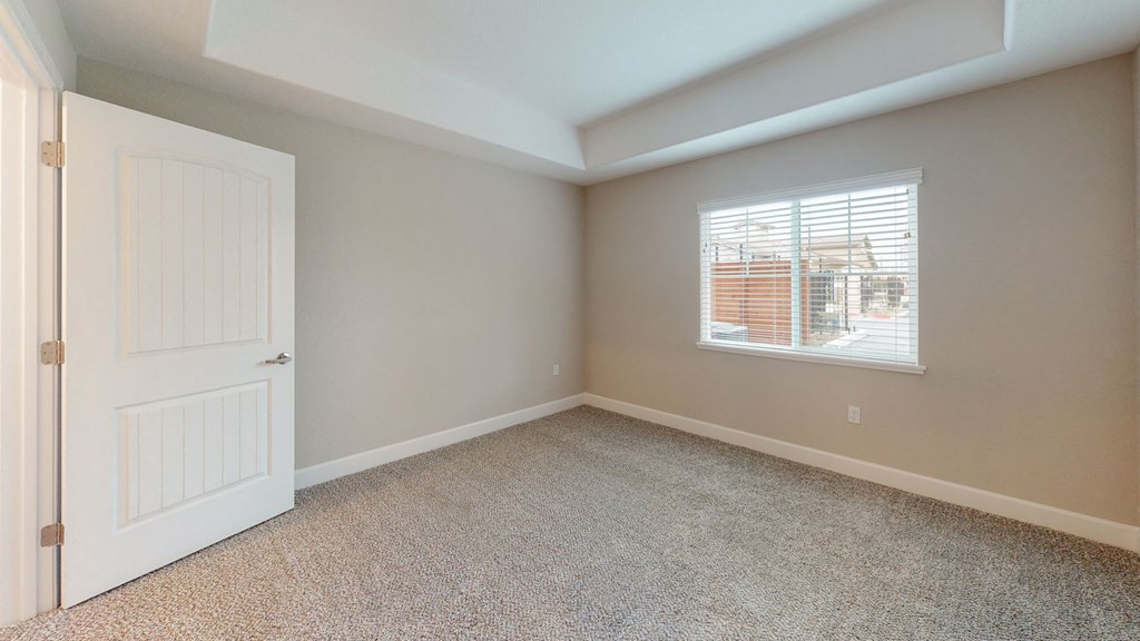 an empty bedroom with a white door and a window at Heritage Landing Apartments, Chico, California