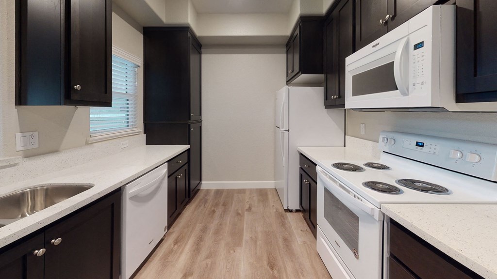 a kitchen with white appliances and black cabinets a kitchen with white appliances and black cabinets at Heritage Landing Apartments, Chico, CA