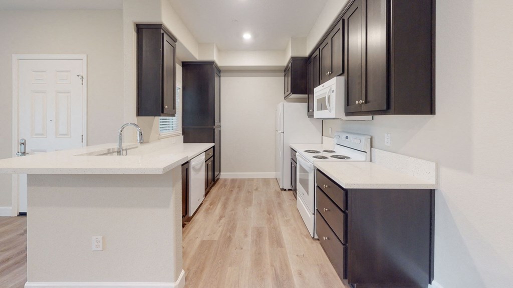 a kitchen with black cabinets and white counter tops and a wood floor at Heritage Landing Apartments, Chico, CA, 95973