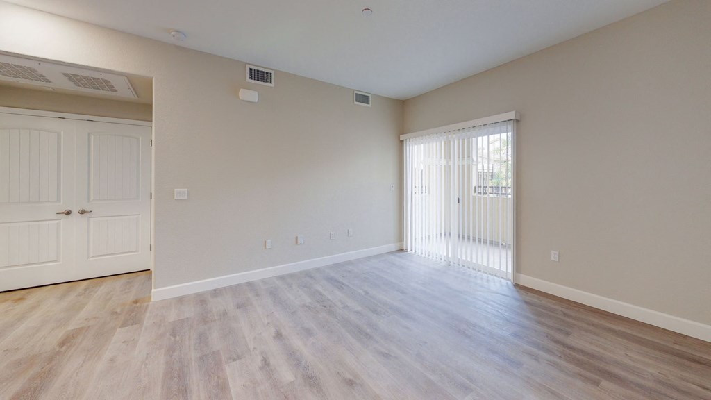 an empty living room with wood floors and a door to a balcony at Heritage Landing Apartments, Chico, CA