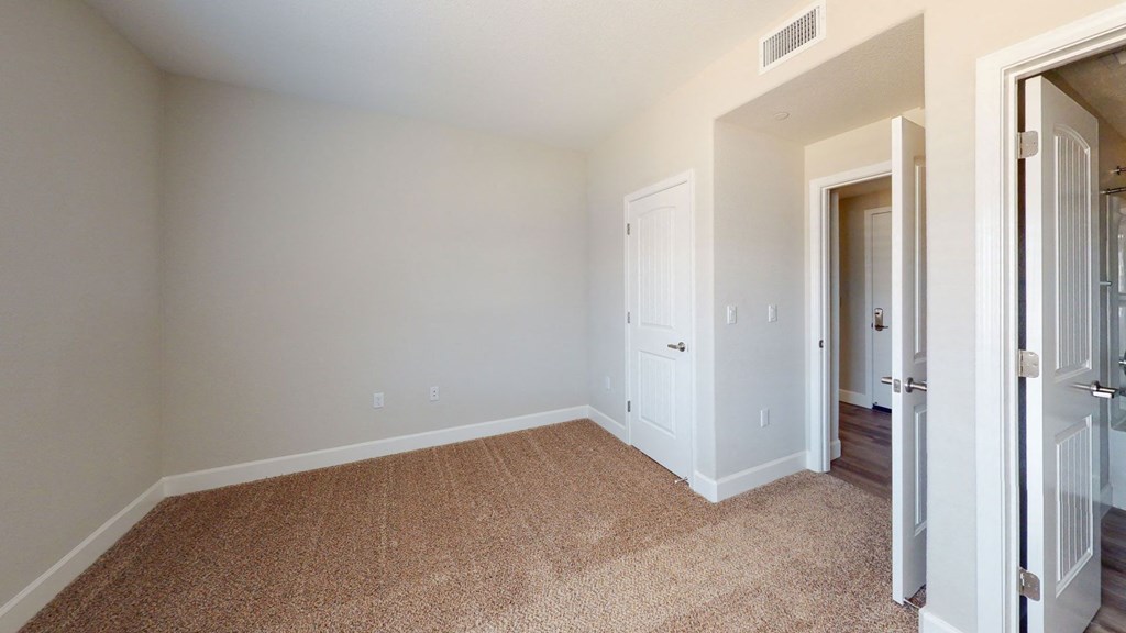 a bedroom with white walls and carpet and a door to a closet at Heritage Landing Apartments, California