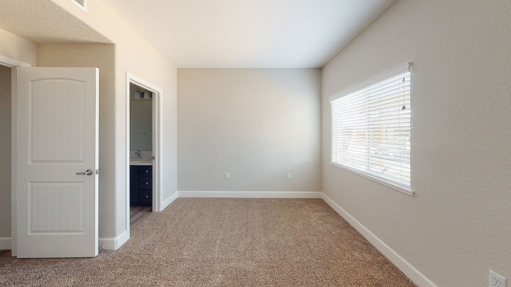 an empty bedroom with a window and a door to a bathroom at Heritage Landing Apartments, Chico, 95973
