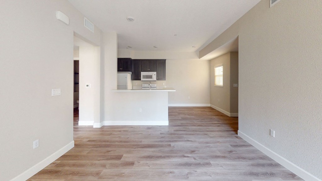 an empty living room and kitchen with white walls and wood flooring at Heritage Landing Apartments, California, 95973