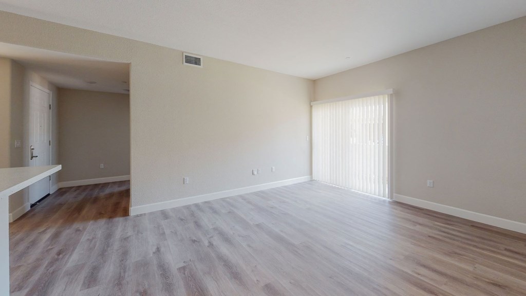 an empty living room with wood flooring and a large window at Heritage Landing Apartments, Chico, California