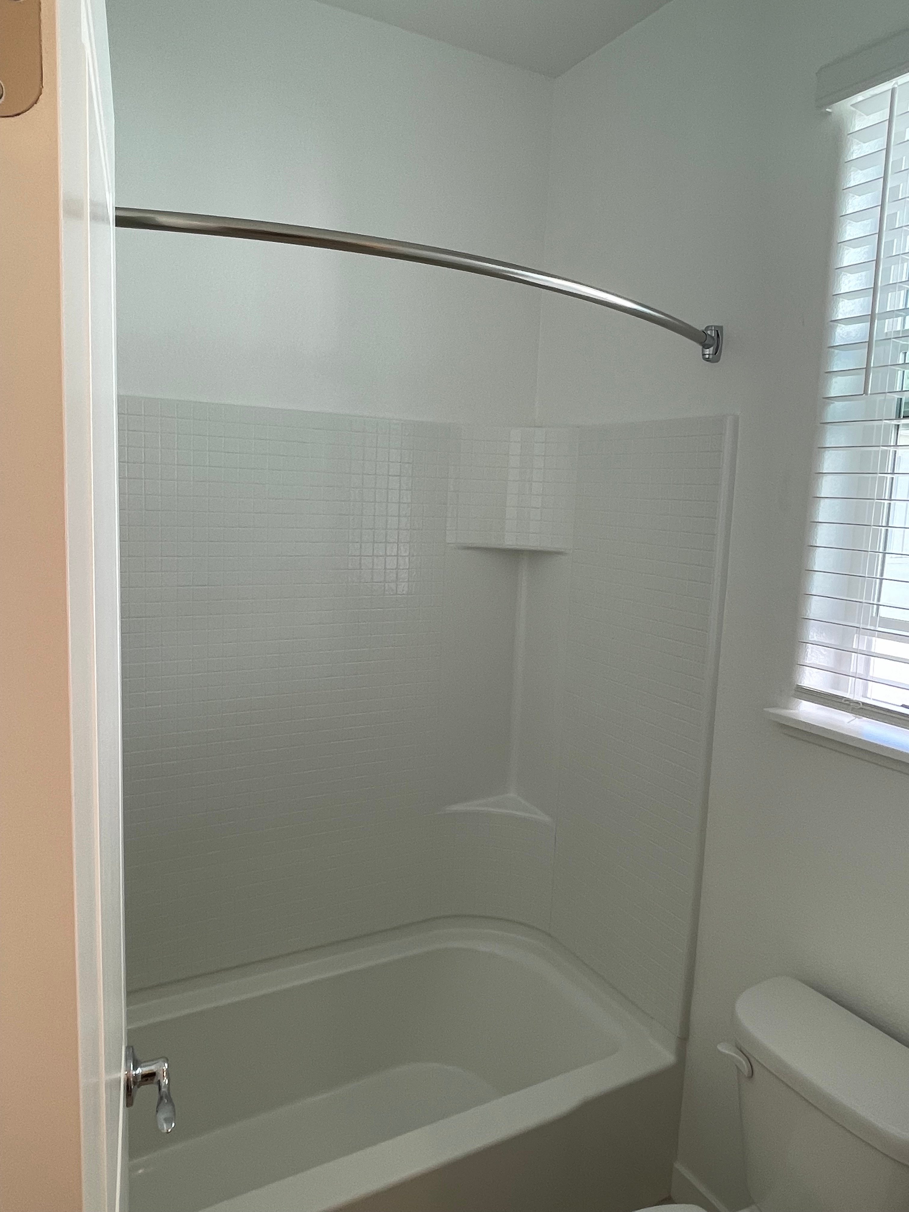 A shower area with a glass door and a metal shower head.