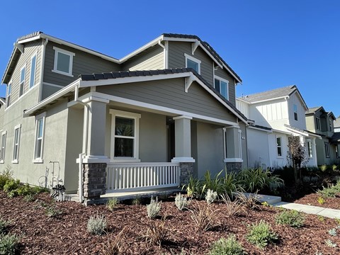 A house with a grey and white exterior and a balcony.