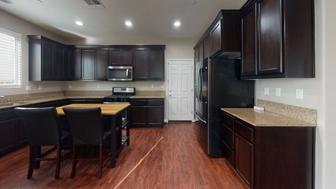A kitchen with dark wood cabinets and a black refrigerator.