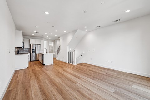 A spacious room with wooden flooring and white walls.