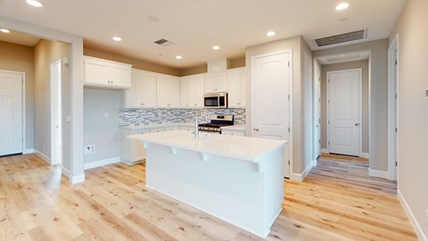A kitchen with a white island and wooden floors.