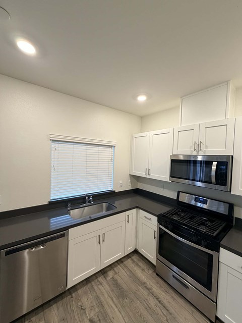 A kitchen with white cabinets and black countertops.