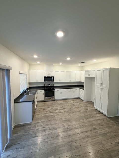 A kitchen with white cabinets and a black countertop.