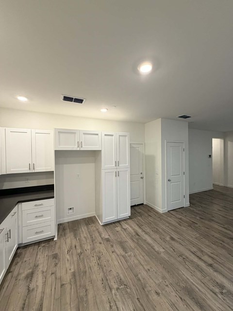 A kitchen with white cabinets and a wooden floor.