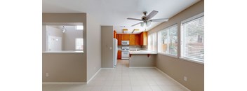 A kitchen with a fan on the ceiling and a dining table with chairs.