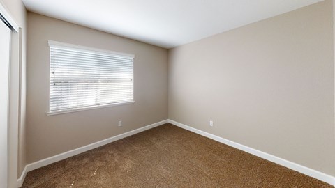 A room with a window and carpeted floor.