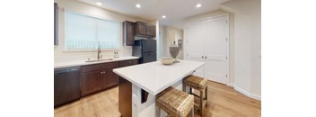 A kitchen with a white table and brown chairs.