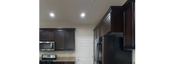 A kitchen with dark brown cabinets and a black refrigerator.