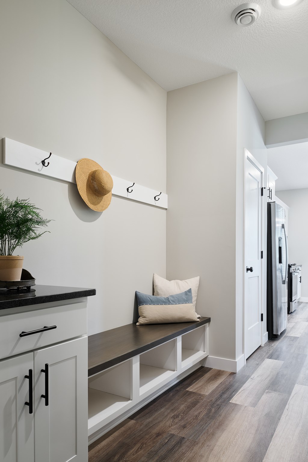 A kitchen with a bench and a hat hanging on a hook.