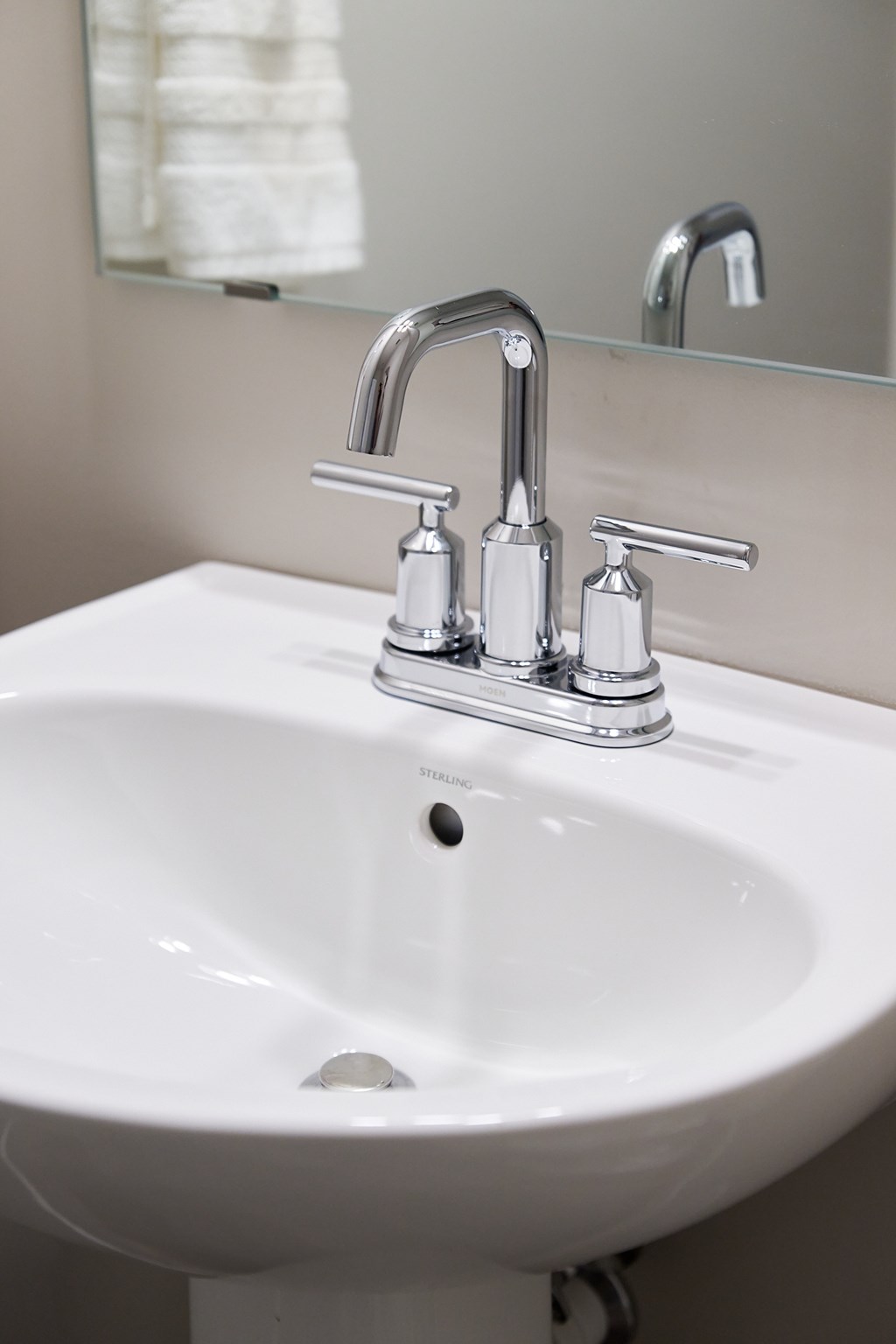 A white sink with a chrome faucet and a mirror above it.