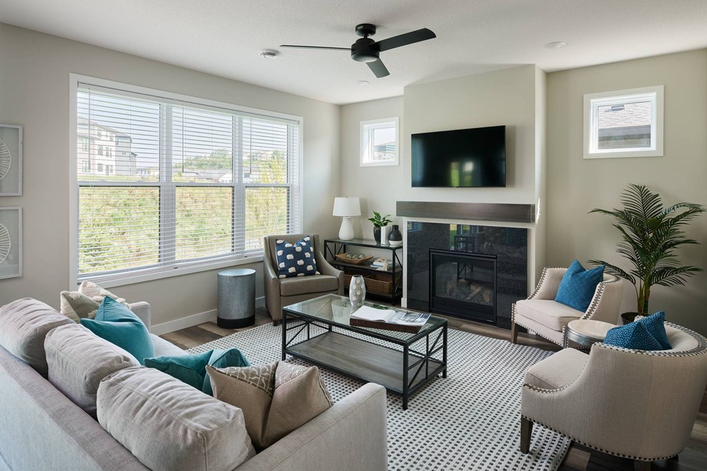 A living room with a fireplace, a television, and a ceiling fan.