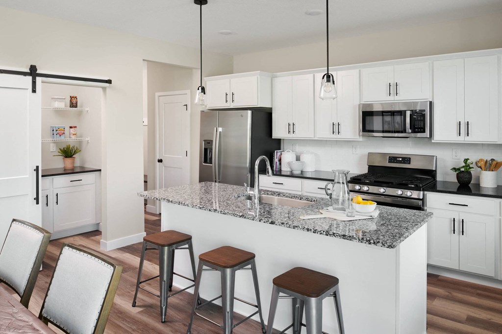 A modern kitchen with white cabinets and a granite countertop.