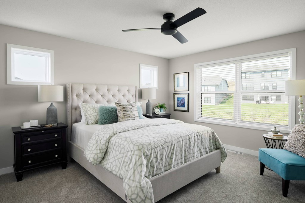 A bedroom with a large bed, a ceiling fan, and a window with blinds.