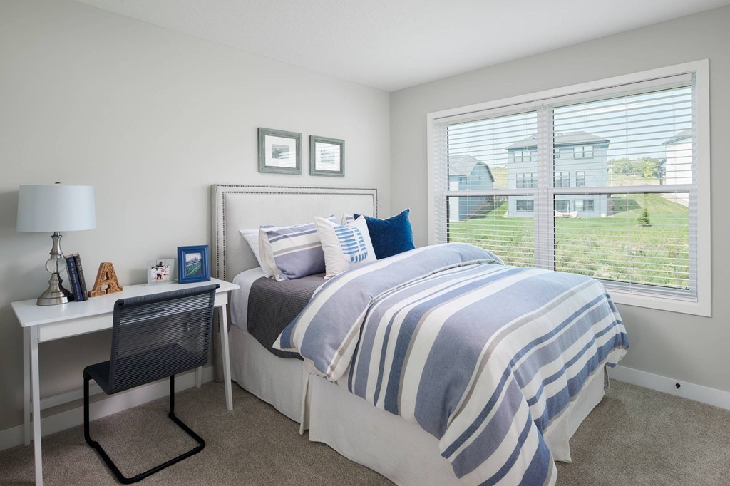 A bedroom with a bed, desk, and chair.