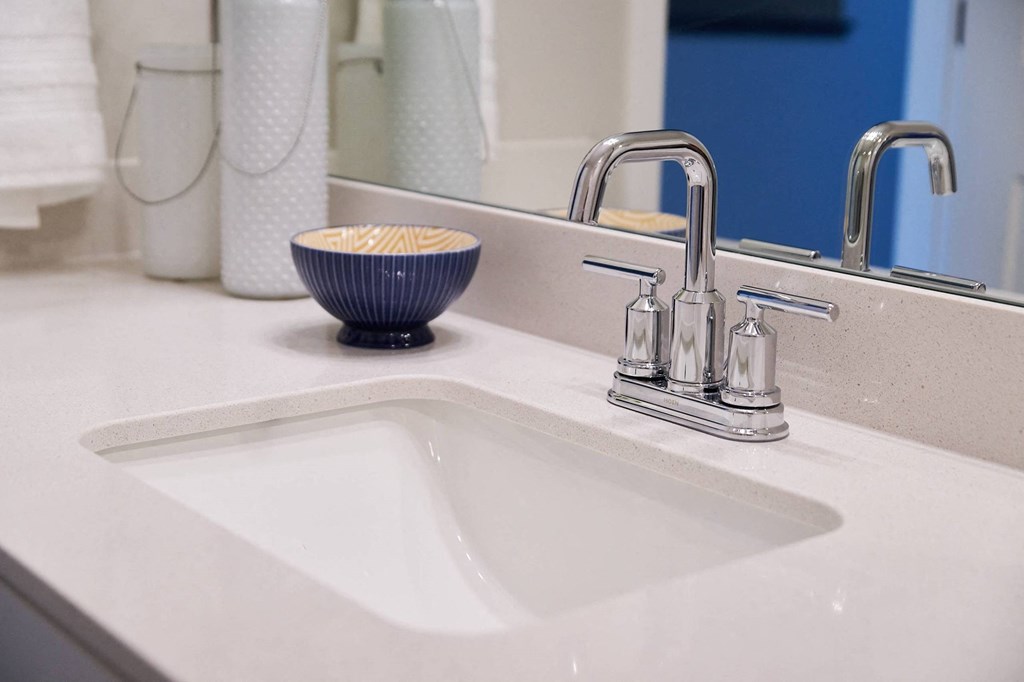 A bowl of cereal sits on a white sink under a mirror.