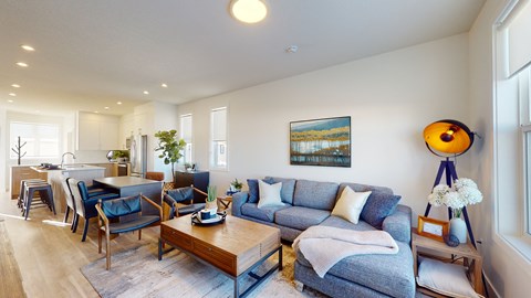 A living room with a blue couch and a painting on the wall.